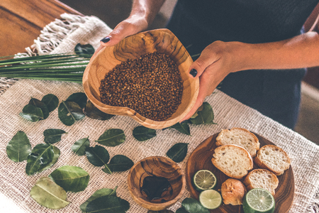 Woman hands with Teak Wooden bowl with buckwheat porridge on table. Traditional russian food. Lime and bread on the table.の写真素材
