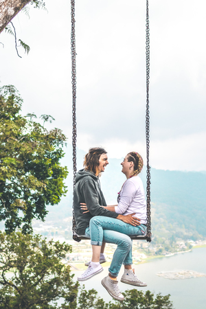 Young honeymoon couple swings in the jungle near the lake, Bali island, Indonesia.の写真素材