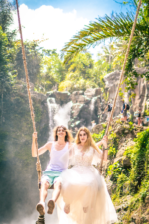 Young honeymoon couple swings in the jungle near the lake, Bali island, Indonesia.の写真素材
