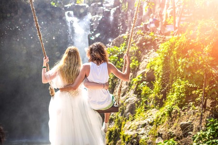 Young honeymoon couple swings in the jungle near the lake, Bali island, Indonesia.の写真素材