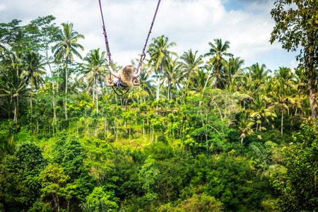 Young tourist woman swinging on the cliff in the jungle rainforest of a tropical Bali island.の写真素材