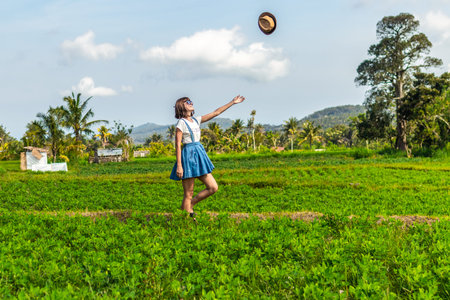 Tropical portrait of young happy woman with straw hat on a road with coconut palms and tropical...
