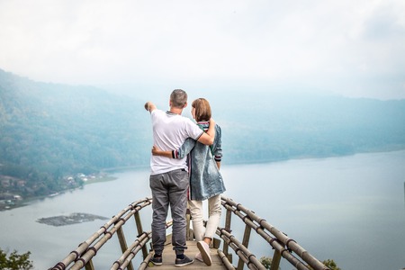 Happy young couple of tourists on the wooden bridge with tropical background. Lake. Bali island.の写真素材