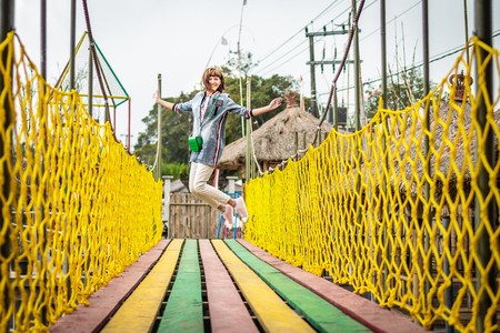 Young woman jumping on a colorful wooden bridge. Bali island.の写真素材