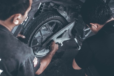 BALI, INDONESIA - AUGUST 29, 2018: Mechanic doing Scooter repairing service.のeditorial素材