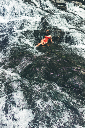 Young woman in red swimsuit on cascade waterfall on Bali island.の写真素材