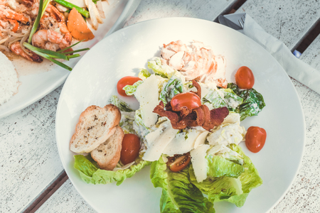 Caesar Salad on a white wooden table in the beach cafe, Bali island. Indonesia.の写真素材