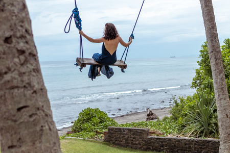 Woman swings on a tropical beach of Bali island, Indonesia.の写真素材