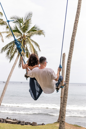 Young couple swinging on the tropical beach of Bali island, Indonesia.の写真素材