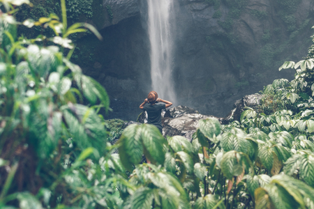 Young woman posing on a great Sekumpul waterfall in the deep rainforest of Bali island, Indonesia.の写真素材
