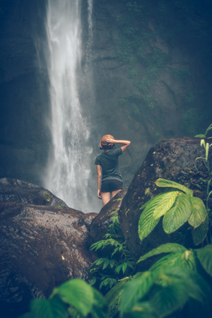 Young woman posing on a great Sekumpul waterfall in the deep rainforest of Bali island, Indonesia.の写真素材