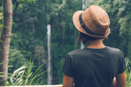 Young woman posing on a great Sekumpul waterfall in the deep rainforest of Bali island, Indonesia.の写真素材