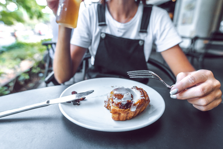 Closeup shot of woman eating cinnamon roll. Delicious dessert, tasty, sugar.の写真素材