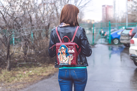 MOSCOW, RUSSIA - APRIL 10, 2019: Young woman with stylish hand painted backpack on the street. Modern City style.のeditorial素材