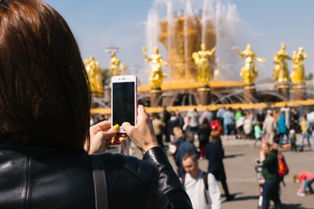 Woman taking photo of Fountain of friendship of nations in VDNH, Russia, Moscow.の写真素材