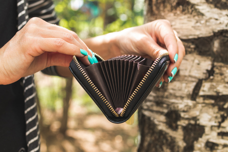 Young woman hands with small wallet card holder on the nature background.の写真素材