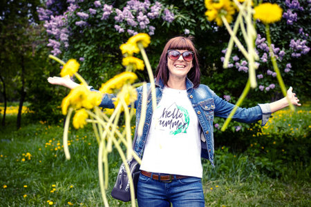 Woman with dandelions in a green spring park outdoors. Young female with yellow dandelions.の写真素材