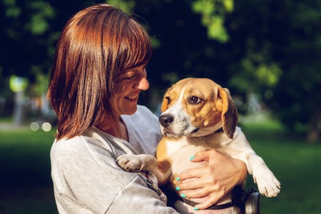 Girl holding a dog in her arms on the nature background at summer time. Lifestyle photo.の写真素材