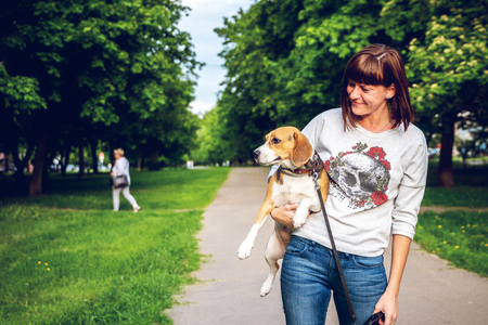Girl holding a dog in her arms on the nature background at summer time. Lifestyle photo.の写真素材