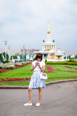 MOSCOW, RUSSIA - MAY 31, 2019: Young woman using smartphone outdoor.のeditorial素材
