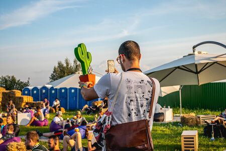 MOSCOW, RUSSIA - JULY 27, 2019: People relaxing at JohnCalliano hookah fest. Man taking photo of cactus.のeditorial素材