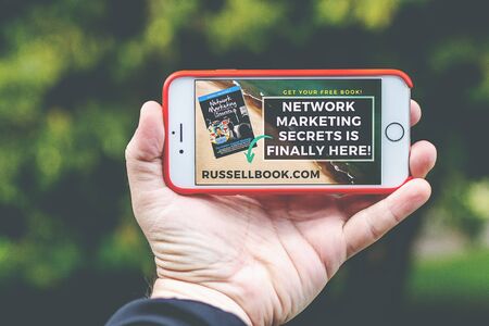 MOSCOW, RUSSIA - AUGUST 6, 2019: Man hand holding smartphone iPhone in red case.のeditorial素材