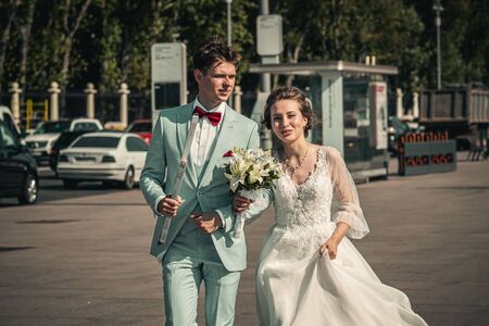 MOSCOW, RUSSIA - AUGUST 30, 2019: Bride and groom walking by city street. Wedding photo.のeditorial素材