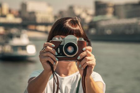 Woman holding retro vintage camera outdoors. Old camera. Beautiful female photography.の写真素材
