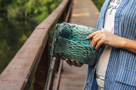 Stylish woman with snakeskin handbag outdoors.