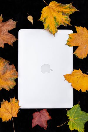 MOSCOW, RUSSIA - OCTOBER 10, 2019: Laptop and autumn leaves on a black background.のeditorial素材