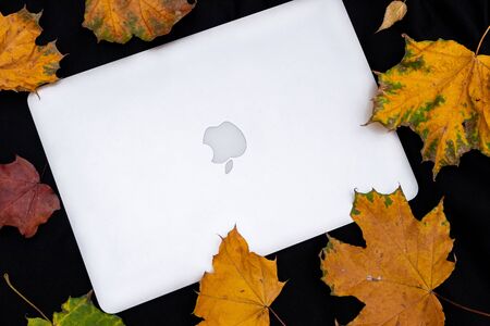 MOSCOW, RUSSIA - OCTOBER 10, 2019: Laptop and autumn leaves on a black background.のeditorial素材