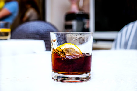 Rum cola casual cocktail with lemon on the white table.