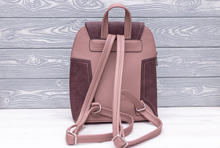 Synthetic leather backpack on a wooden background.