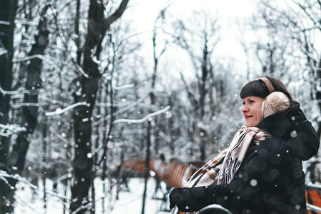 Woman portrait in snowing weather. Girl in the park at winter time. Winter female portrait.