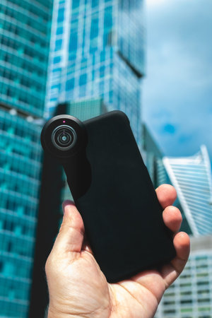 Man hand holding smartphone on a skyscraper background. Corporate stock image.