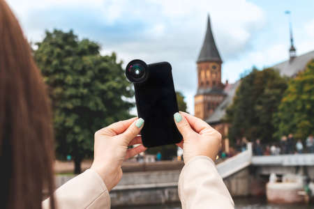 Female hand holding black smartphone on a city background.の写真素材