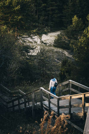 A beautiful vertical image of young female goes down the wooden stairs in a deep forest.の写真素材