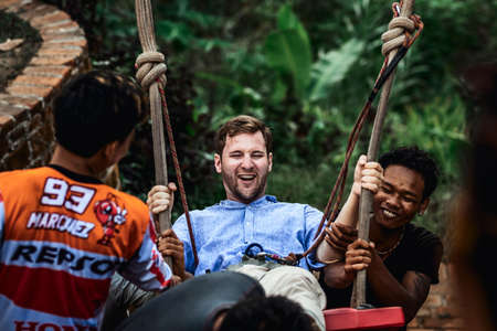 BALI, INDONESIA - MAY 16, 2018: Young man swinging in the jungle rainforest of Bali island, Indonesia. Swing in the tropics. Swings - trend of Bali island.のeditorial素材