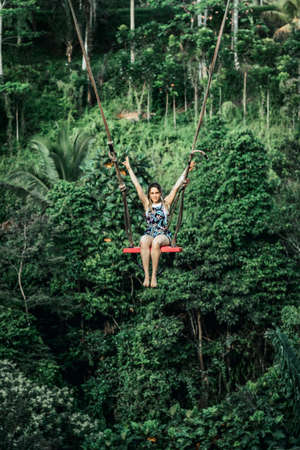 BALI, INDONESIA - MAY 16, 2018: Young woman swings in the jungle of Bali island. Rainforest of Indonesia. Travel concept.のeditorial素材