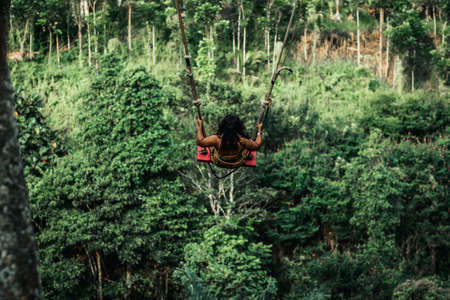 Young woman swings in the jungle of Bali island. Rainforest of Indonesia. Travel concept.の写真素材