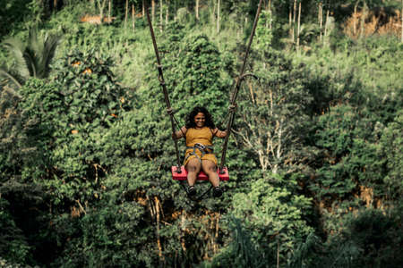 BALI, INDONESIA - MAY 16, 2018: Young woman swings in the jungle of Bali island. Rainforest of Indonesia. Travel concept.のeditorial素材