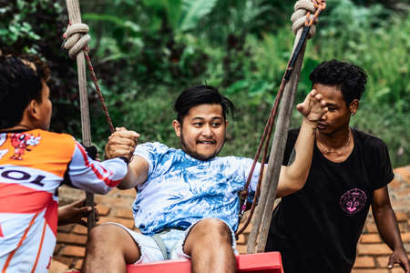 BALI, INDONESIA - MAY 16, 2018: Young man swinging in the jungle rainforest of Bali island, Indonesia. Swing in the tropics. Swings - trend of Bali island.のeditorial素材