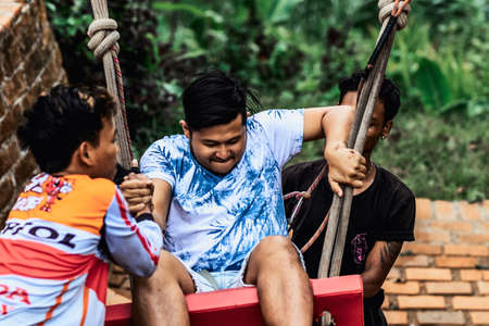 BALI, INDONESIA - MAY 16, 2018: Young man swinging in the jungle rainforest of Bali island, Indonesia. Swing in the tropics. Swings - trend of Bali island.のeditorial素材
