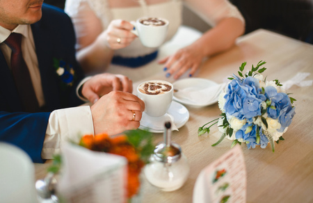 Wedding couple in a cafe drinking coffee with foam in the shape of heartの写真素材