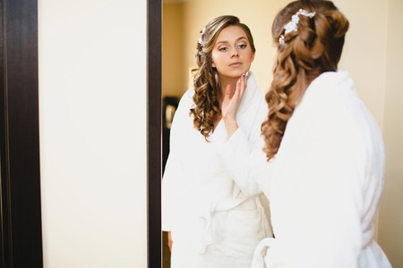 The girl in white coat at the mirror preeningの写真素材