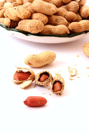 peanuts with shells on the plate isolated on whiteの写真素材