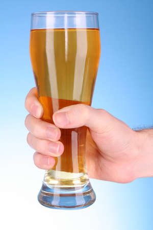 Cup of beer in hand on blue backgroundの写真素材