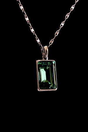 Square pendant with green gem isolated on blackの写真素材
