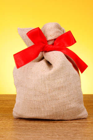 Hessian sack tied with a red ribbon on yellow backgroundの写真素材
