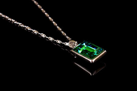Square pendant with green gem isolated on blackの写真素材